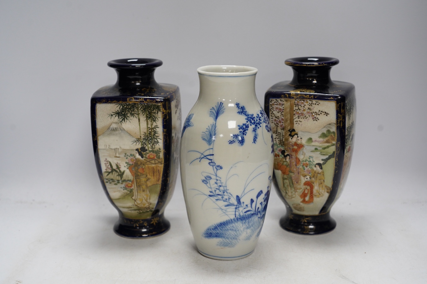 A pair of Japanese satsuma pottery vases and a blue and white Meiji Arita vase, largest 24cm high. Condition - fair